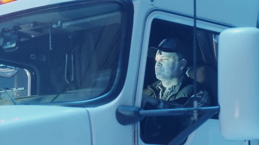 Man sits in a semi truck illuminated by blue light
