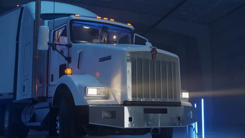 A man is entering a semi-truck in a warehouse lighted with fluorescent lights