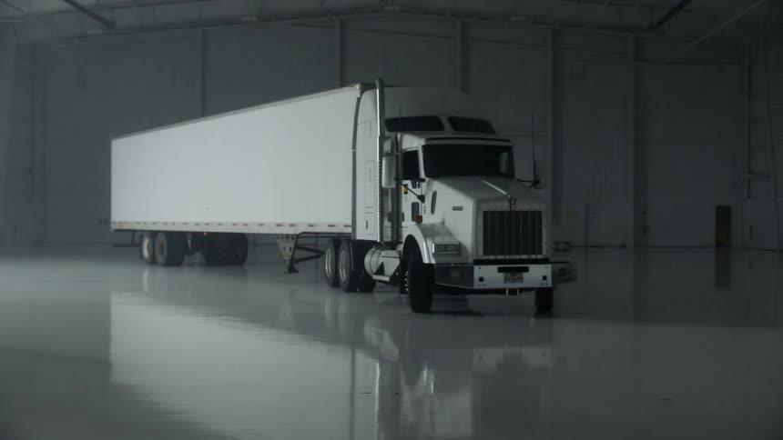 A semi-truck is parked in a warehouse