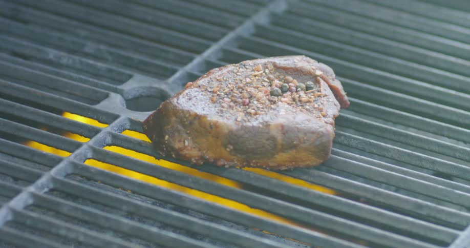 Thick steak cooks on the grill