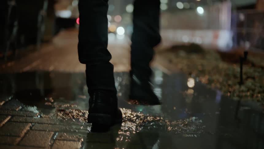A man steps in a puddle on a city sidewalk