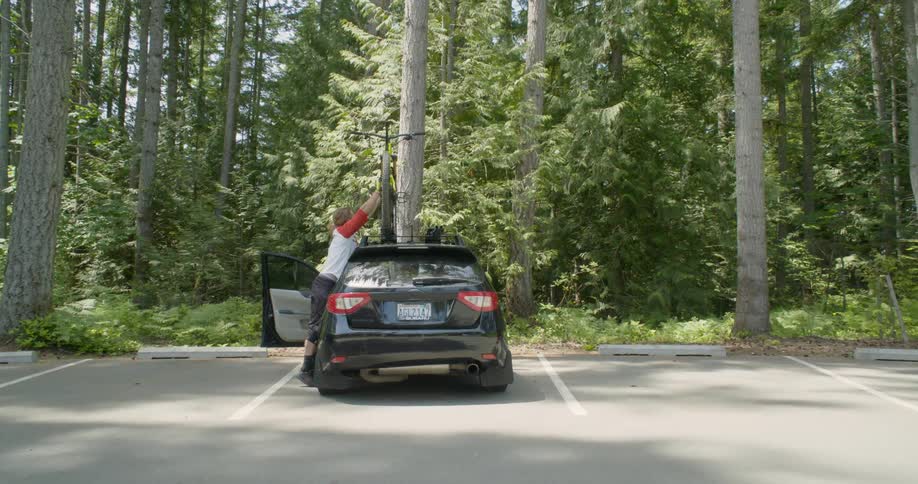 A man reaches up to remove his bike from the car