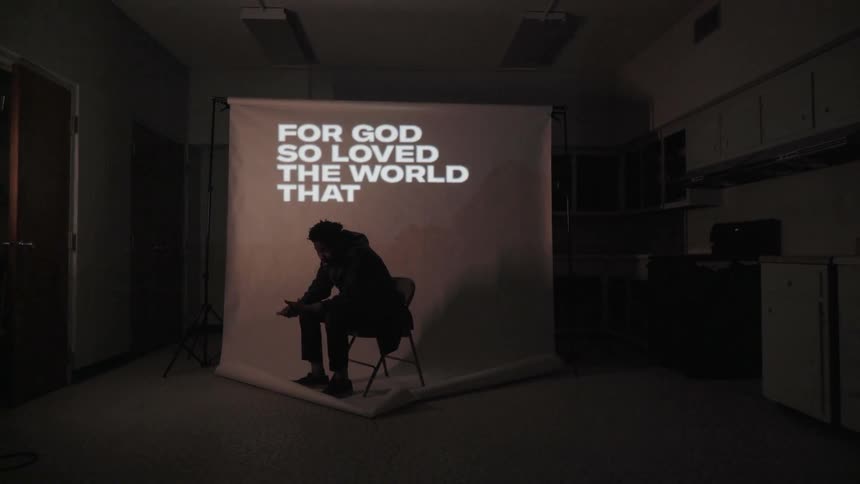 A man sits in front of a projection screen as words flash