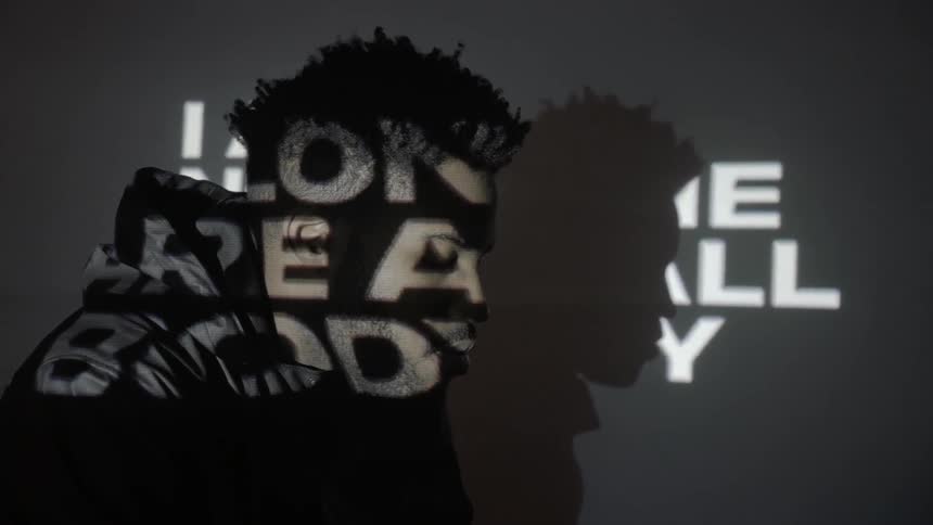 Words are projected onto a man's face in the dark
