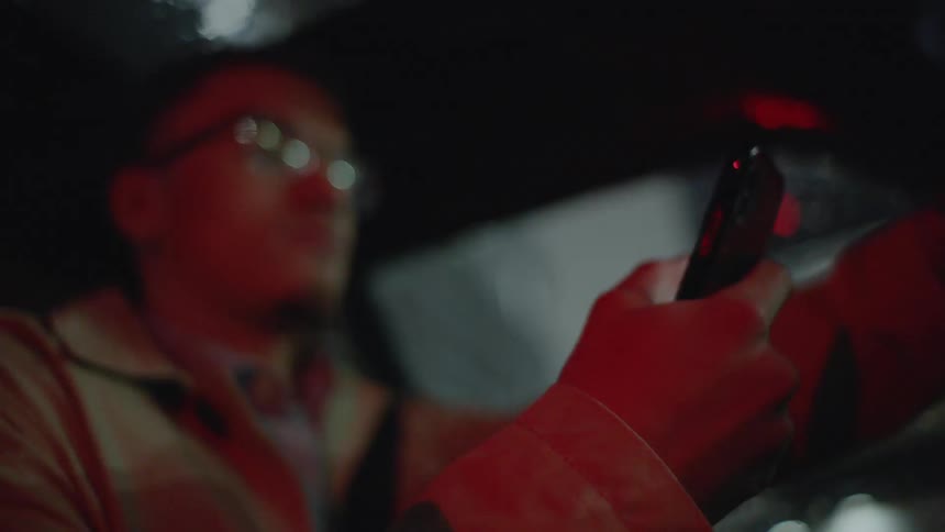 Man in car types on smartphone