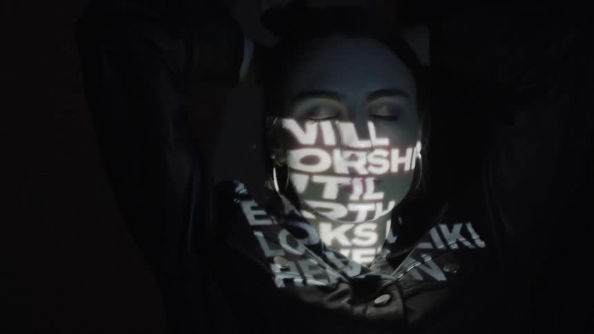 Words are projected onto a woman's face in the dark