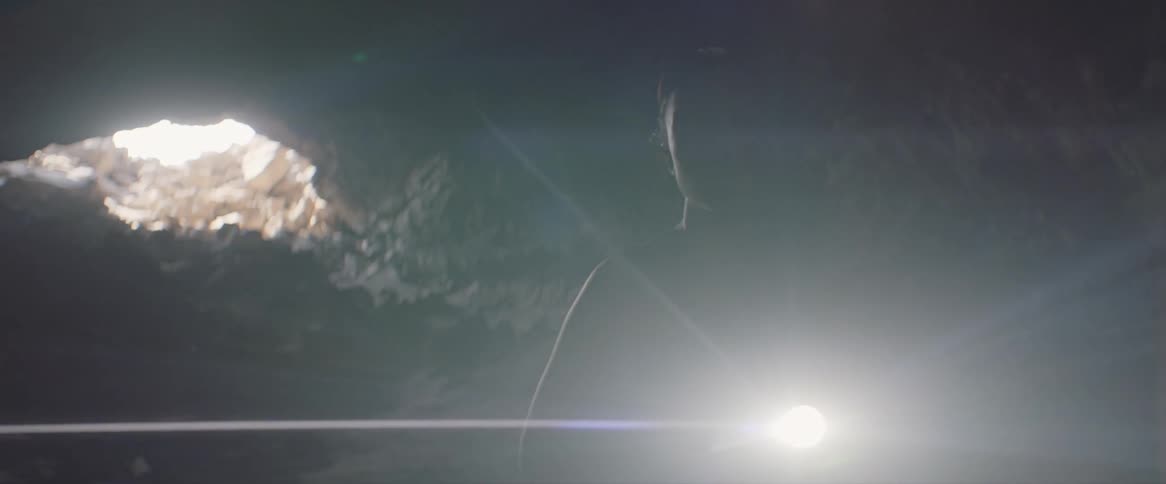 Woman carries a flashlight into a dark cave