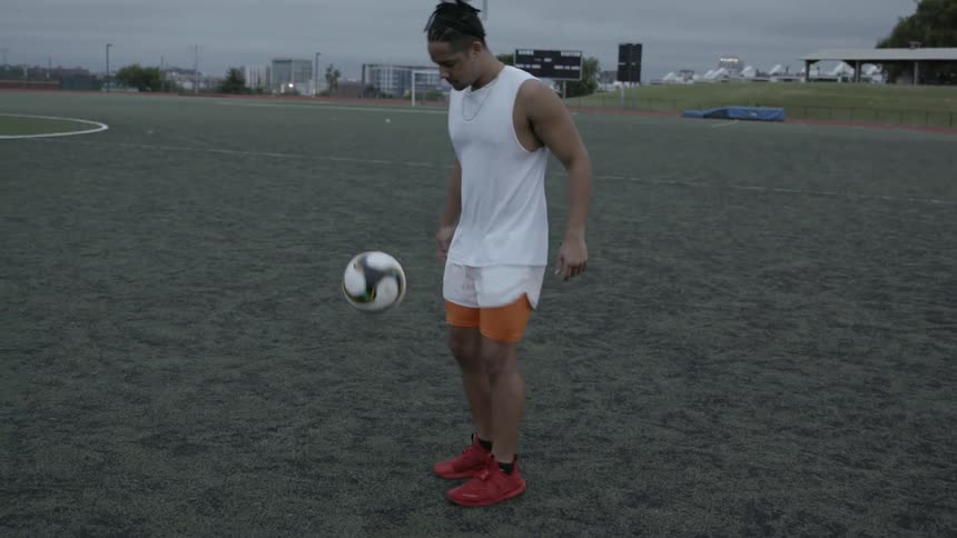 A soccer player kicks a ball on an outdoor field