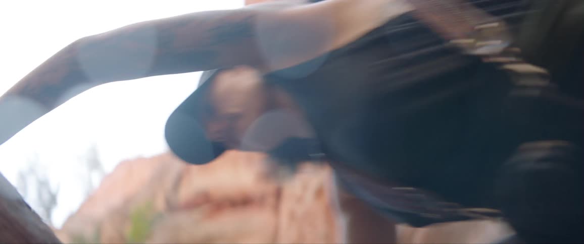 A woman climbs over rocks with a camera