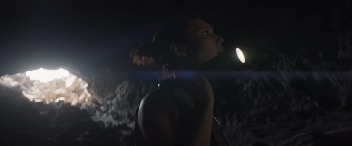 Woman shines a flashlight as she walks in a cave