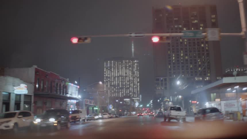 Traveling past cars and people on a city street at night