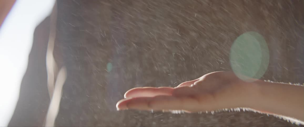A person waves their hand in the rain