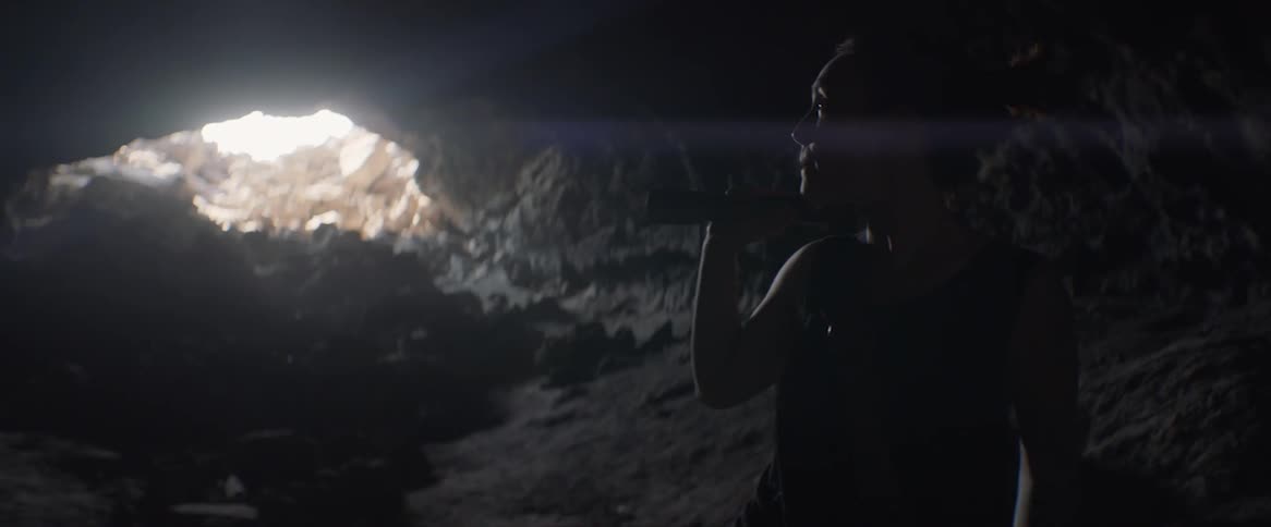 A woman looks around a cavern with a flashlight