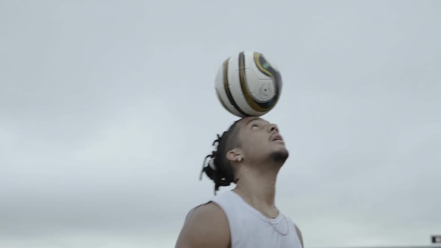 A man balances a soccer ball on his forehead