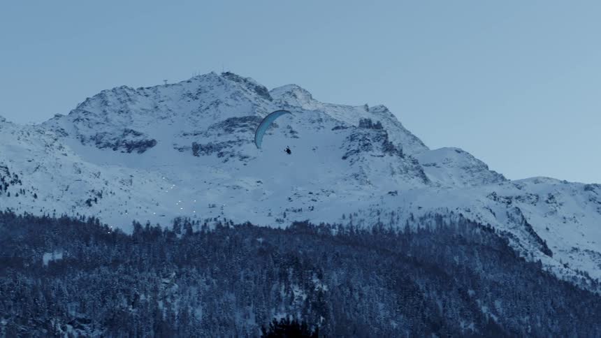 A parachuter glides down from the mountain