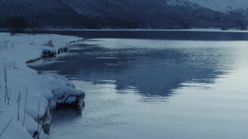 Water ripples gently near the snowy shore