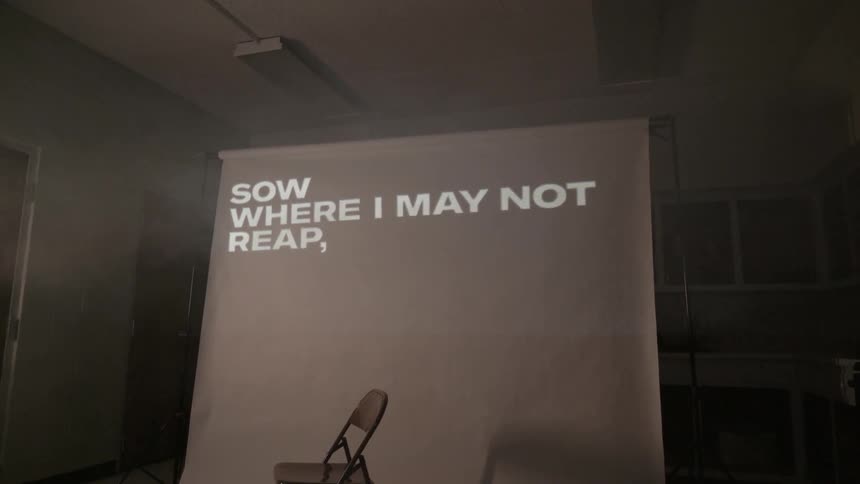Words are being displayed on a screen behind a chair in a room