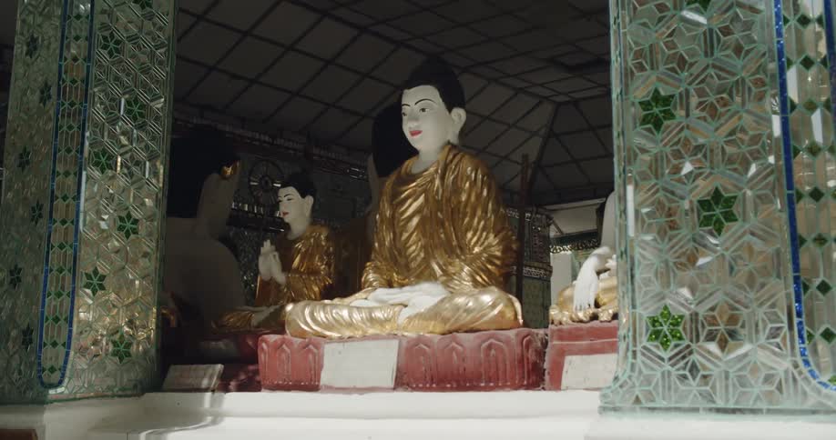 Statues in a buddhist temple are sitting beneath an arch in daylight