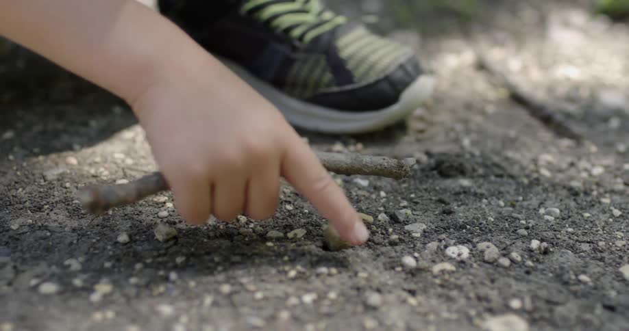Child digs on the dirt ground with a stick
