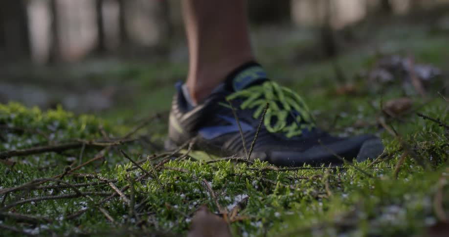 Man in running shoes walks on the twigs and the grass