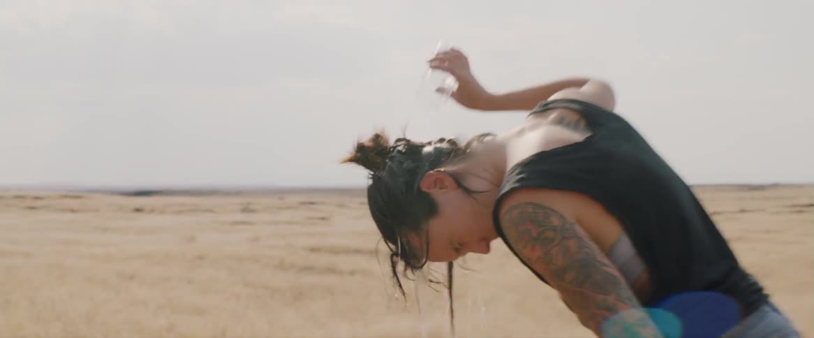 Woman with a tattoo pours water on her head
