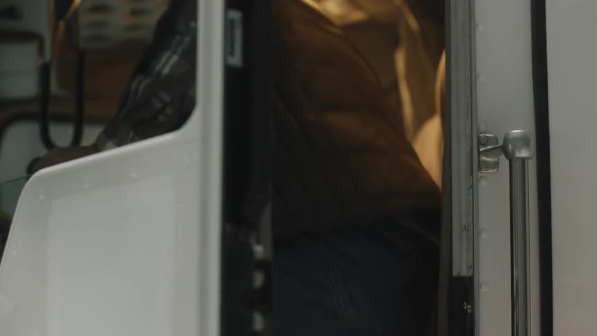 Man opens the door of a semi truck and climbs in