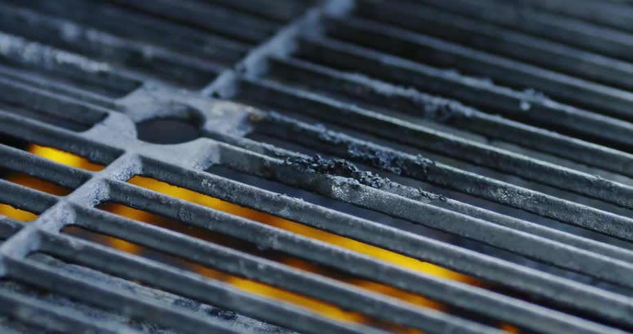 Smoke rises from a flaming grill when something is placed on it