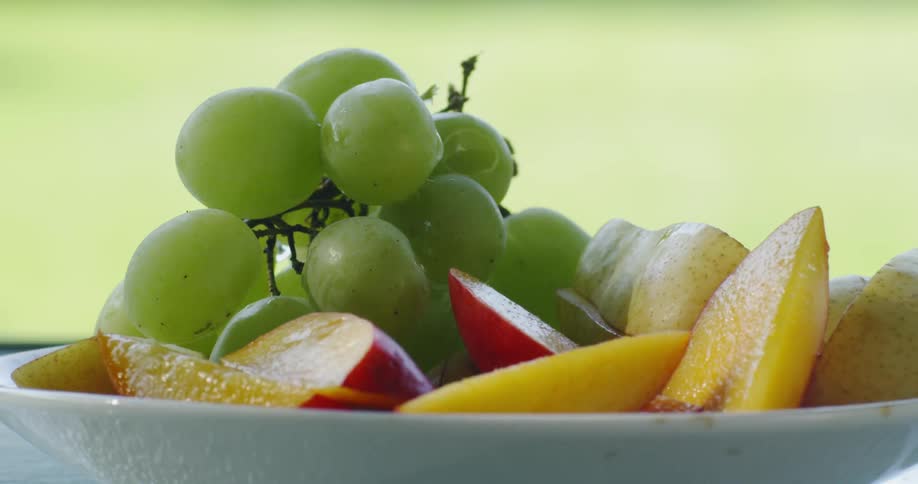 Grapes and peaches in a bowl on a table outside