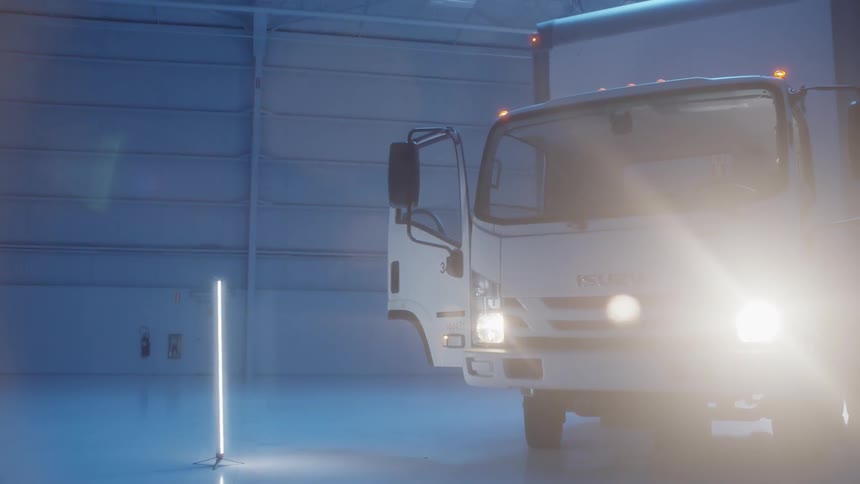 A box truck sits with its lights in inside a garage