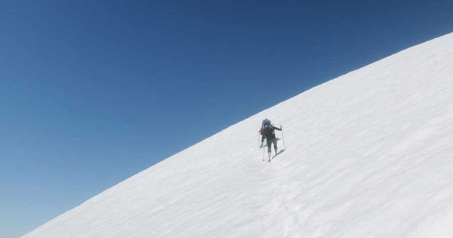 Hikers climb up a snowy mountainside