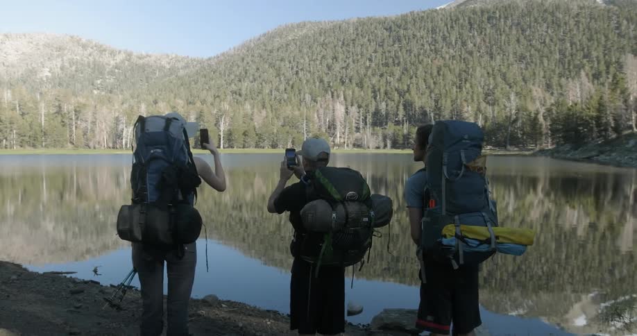 Three hikers look out towards the lake