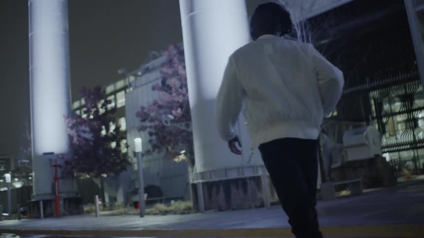 A man walks on a city sidewalk at night