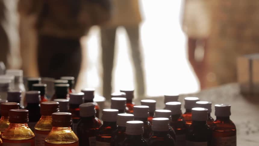 A man is placing bottles on a counter inside a shop in daylight