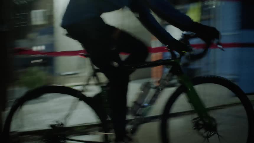 A man rides a bicycle in the city at night