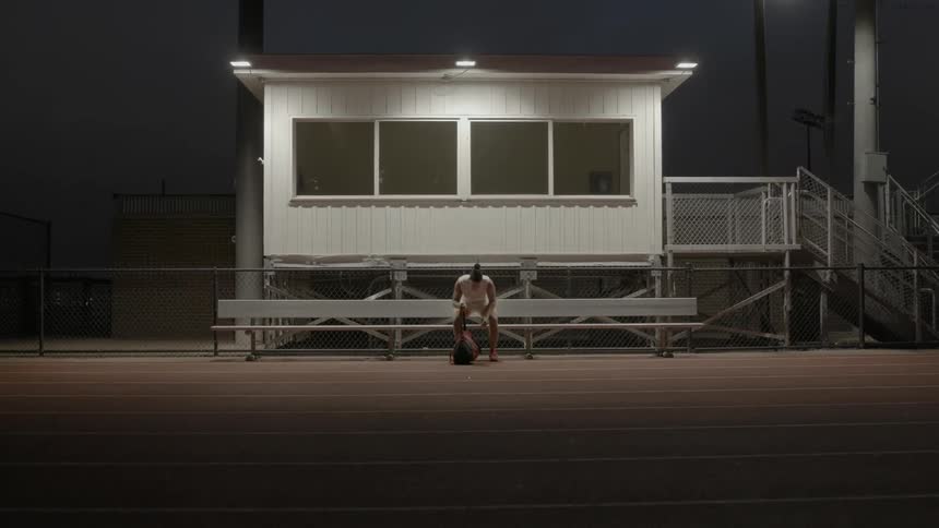 A man sits down on the bench and drops his bag