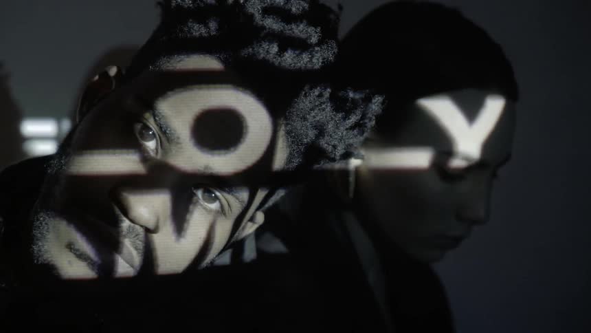 Words are projected onto a man and woman's face in the dark