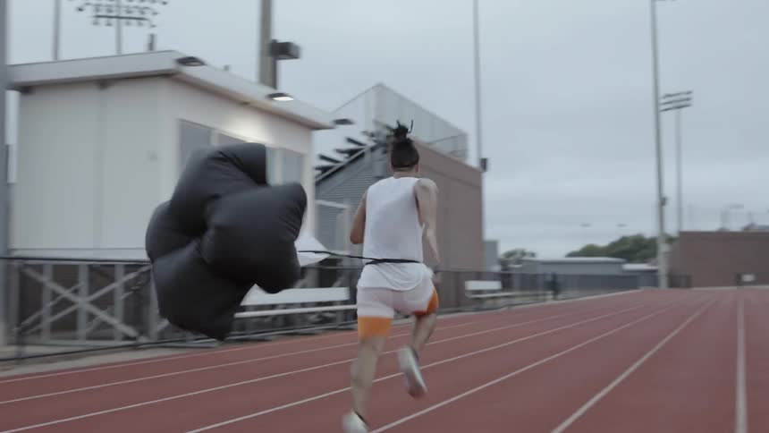 An athlete runs on the track with a small parachute