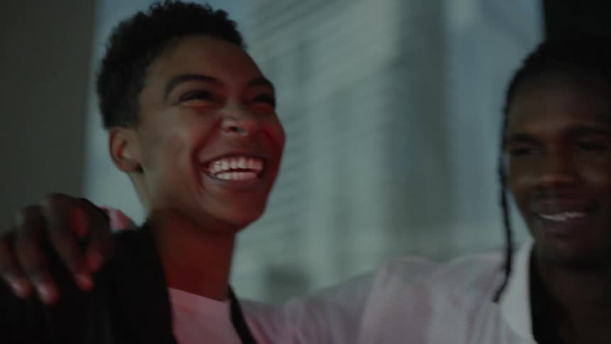 A man and woman smile and laugh outside at night