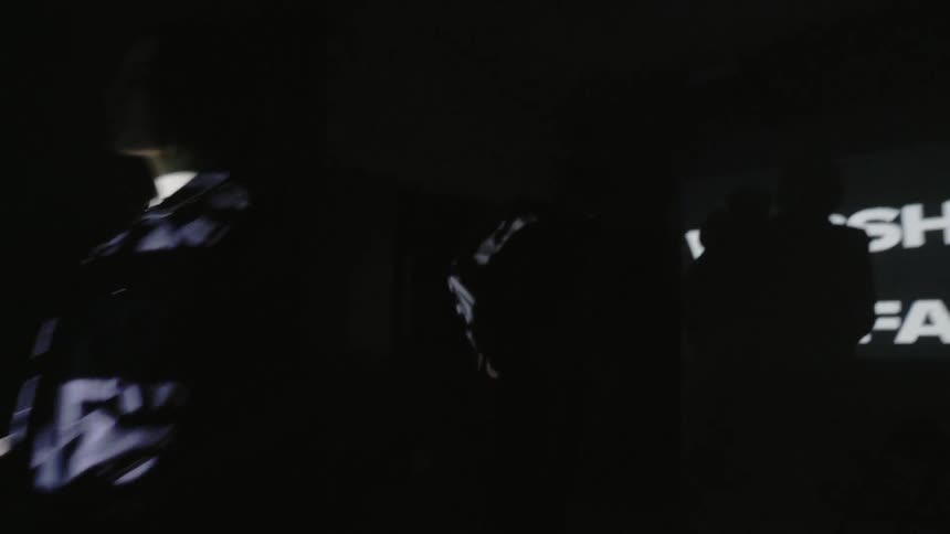 People walk in front of a projection screen with text
