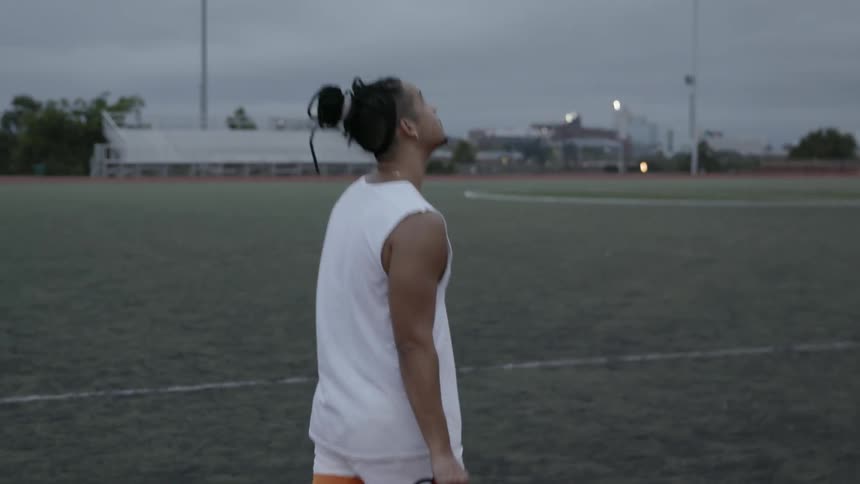 Man walks in a field as he bounces a soccer ball