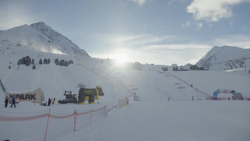 The sun is peeking over a slope in a ski resort in daylight