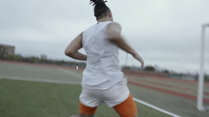 An athlete is running sprints on a soccer field on a cloudy day