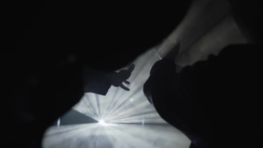 People reach in front of a projected light