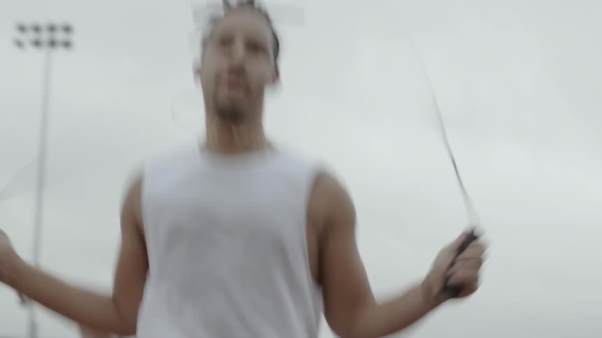 A man jumping rope in a park on a cloudy afternoon