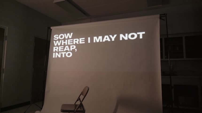 Words are being displayed on a screen behind a chair in a room