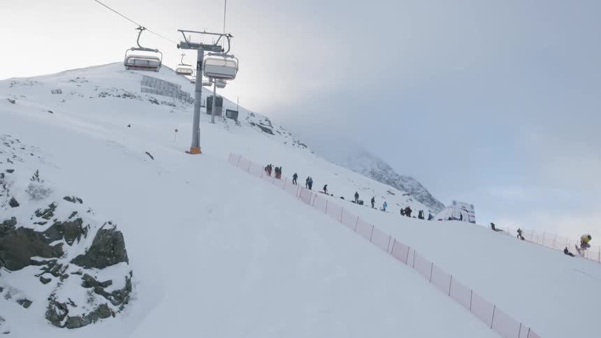 A ski lift is operating on the slopes of a mountain in daylight