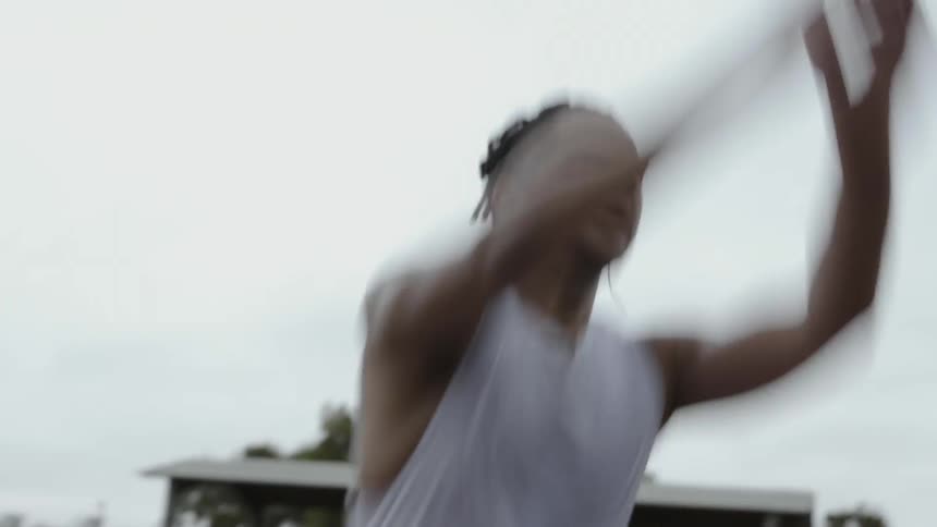 A male athlete is jumping on an athletic field on a cloudy day