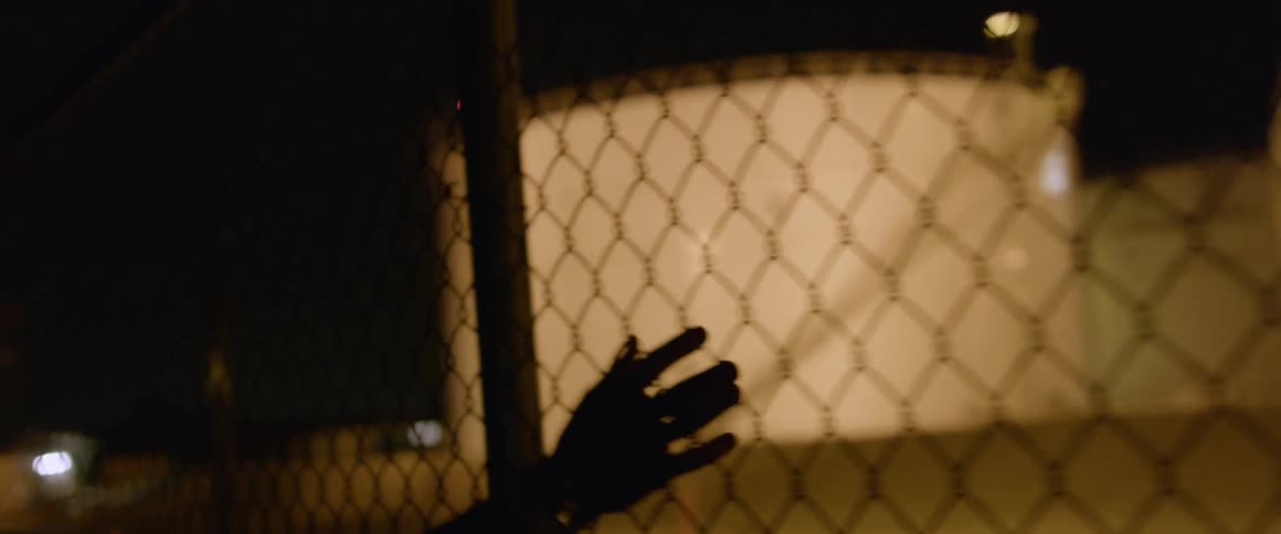 A man walks up to a tall security fence