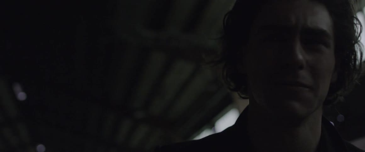 A man stands in a dark building looking distressed
