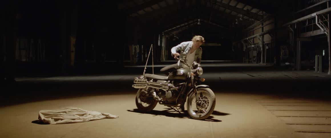 Man puts on a jacket and then climbs onto a motorcycle